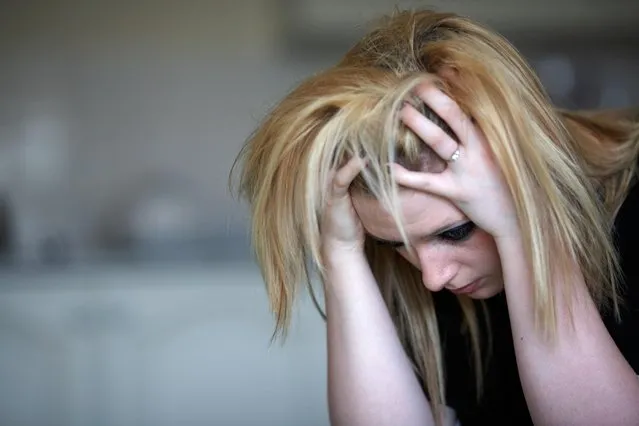 Close up of the head and shoulders of young blonde haired teenage woman sitting with head in her hands at home in her kitchen. (Photo by Radharc Images/Alamy Stock Photo)