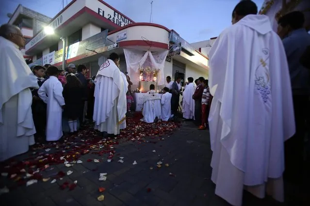 In this June 4, 2015 photo, after the indigenous dancers are long gone, Catholic priests take part in a procession through the streets of Pujili, Ecuador, continuing with the the Catholic ritual of the Corpus Christi festivities. Although eight of 10 people in Ecuador say they are Catholic, a recent Corpus Christi festival in the city of Pujilli featured joyous dances and ceremonial acts of thanks to the ancient native god Inti, or Father Sun. (Photo by Dolores Ochoa/AP Photo)