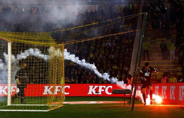 Nantes' French goalkeeper Remy Descamps passes by a flare launched by supporters during the French Cup semi-final football match between FC Nantes and AS Monaco at the La Beaujoire Stadium in Nantes, western France on March 2, 2022. (Photo by Stephane Mahe/Reuters)