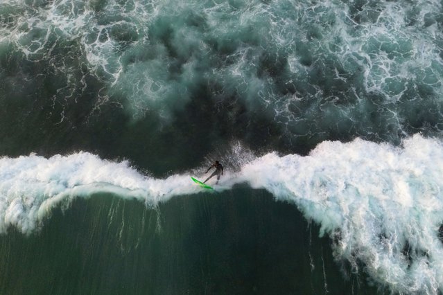 An aerial view of a surfer surfing among the giant waves of Atlantic Ocean in Dakar, Senegal on May 25, 2024. In Senegal, which has 724 kilometres of coastline, surf schools with large and small beaches along the coastline are flooded by surfing enthusiasts. Surfers gather at the beach at noon enjoy the sea until the evening hours as the waves grow. (Photo by Cem Ozdel/Anadolu via Getty Images)