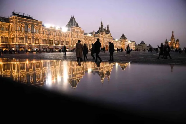 People walk in Red Square near the GUM, the State Shop, left, which is closed due to COVID-19, the St. Basil's Cathedral, right, after sunset in Moscow, Russia, Monday, November 1, 2021. To contain the spread of COVID-19, Russian President Vladimir Putin ordered a nonworking period from Oct. 30 to Nov. 7, when most state agencies and private businesses are to suspend operations. Moscow introduced the measure beginning Thursday, shutting down kindergartens, schools, gyms, entertainment venues and most stores, and restricting restaurants to takeout or delivery. (Photo by Alexander Zemlianichenko/AP Photo)