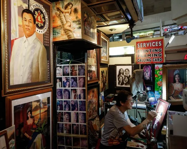 Filipino artist Freddie Luna Cruz (R) works on a portrait along a painting of President-elect Rodrigo Duterte (L) in his shop at a mall in Manila, Philippines, 27 May 2016. Freddie Luna Cruz, great grandson of Philippine National Artist Juan Luna took two weeks to finish his painting, a 20 x 30 inches oil on canvass of Philippine President-elect Rodrigo Duterte. Cruz has received many offers for the painting but refused as he hopes to present it as a gift on Duterte's inauguration on 30 June. (Photo by Mark R. Cristino/EPA)