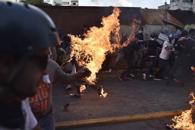 Opposition demonstrators set an alleged thief on fire during a protest against the government of President Nicolas Maduro in Caracas on May 20, 2017. According to the Venezuelan Interior and Justice Ministry the victim, Orlando Figuera, 21, who was set on fire accused of being a chavist or a thief, remains at hospital with first and second degree burns in 80% of his body and several stab wounds. (Photo by Carlos Becerra/AFP Photo)