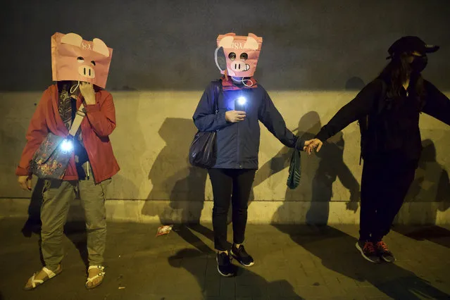Protesters wear masks as they join hands to form a human chain during a rally in Hong Kong, Saturday, November 30, 2019. (Photo by Ng Han Guan/AP Photo)