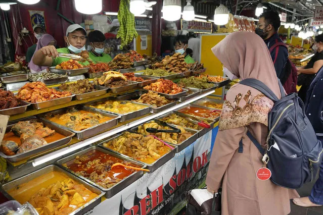 A worker serves customers iftar meals to break their fast at a roadside food court during Ramadan in Jakarta, Indonesia, Wednesday, April 13, 2022. Muslims around the world are observing Ramadan, the holiest month in Islamic calendar, where they refrain from eating, drinking, smoking, and s*x from dawn to dusk. (Photo by Achmad Ibrahim/AP Photo)