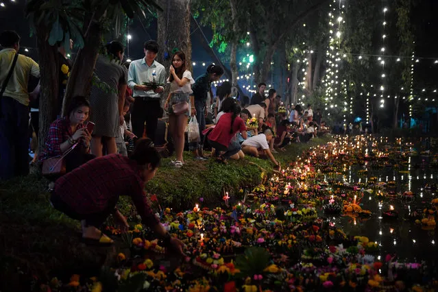 People place krathongs, or floating baskets, in a pond to mark the annual Loy Krathong festival in Bangkok on November 11, 2019. Loy Krathong takes place on the evening of the full moon of the 12th month in the traditional Thai calendar, which usualy falls in November. (Photo by Lillian Suwanrumpha/AFP Photo)