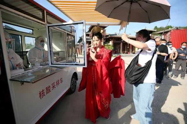 Crew members line up to get tested for the coronavirus disease (COVID-19) at a mobile nucleic acid testing vehicle inside Hengdian World Studios in Hengdian, Zhejiang province, China on May 3, 2022. (Photo by China Daily via Reuters)