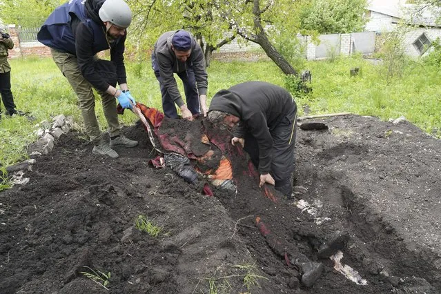 Police and volunteers exhume the bodies of civilians killed by Russian shelling in the village of Stepaky, close to Kharkiv, Ukraine, Wednesday, May 11, 2022. (Photo by Andrii Marienko/AP Photo)