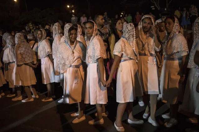 Catholic women hold hands during a procession commemorating the feast day of Our Lady of Chiquinquirá, the patron saint of Zulia state, in downtown Maracaibo, Venezuela, November 18, 2019. Opposition leader Juan Guaidó this year launched a campaign promising to oust President Nicolás Maduro and return the nation to its bygone prosperity. While the power struggle plays out, millions of Venezuelans remain caught in the middle. (Photo by Rodrigo Abd/AP Photo)