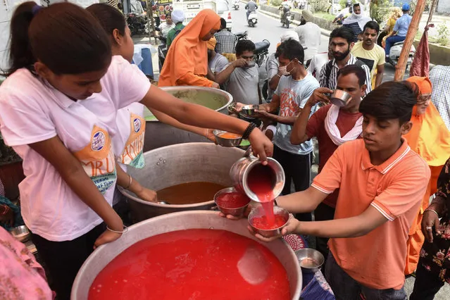 Volunteers dristribute cold sweet drinks to people during a hot summer day in Amritsar on May 18, 2022. (Photo by Narinder Nanu/AFP Photo)