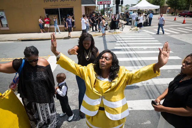 Annette Stubbs, a pastor at a local church, prays for victims a few blocks from a crime scene at the nightclub where a mass shooting took place the night before, along with members of her church, in Orlando, Fla., Sunday, June 12, 2016. A gunman opened fire inside the gay nightclub early Sunday, killing at least 50 people before dying in a gunfight with SWAT officers, police said. (Photo by Loren Elliott/Tampa Bay Times via AP Photo)