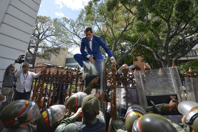 National Assembly President Juan Guaido, Venezuela's opposition leader, tries to climb the fence to enter the compound of the Assembly, after he and other opposition lawmakers were blocked by police from entering a session to elect new Assembly leadership in Caracas, Venezuela, Sunday, January 5, 2020. With Guaido stuck outside, a rival slate headed by lawmaker Luis Parra swore themselves in as leaders of the single-chamber legislature. (Photo by Matias Delacroix/AP Photo)