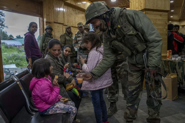 An Indian army soldier offers juice to an Indian tourist girl after she along with her family was rescued from a cable car in Gulmarg, northwest of Srinagar, Indian controlled Kashmir, Sunday, June 25, 2017. (Photo by Dar Yasin/AP Photo)