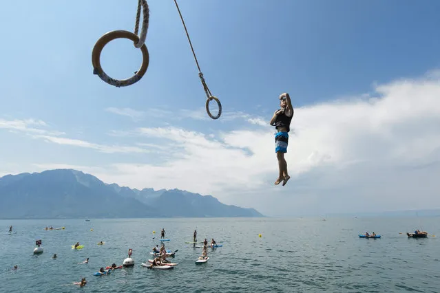 A gymnast swings on rings and then jumps into Lake Geneva at the WateRings Contest, a fun contest, in Montreux, Switzerland, 08 August 2015. (Photo by Jean-Christophe Bott/EPA)