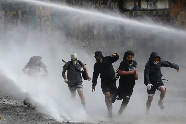 Demonstrators are sprayed by riot police with a water cannon during an anti-government protests in Santiago, Chile on January 18, 2020. (Photo by Edgard Garrido/Reuters)