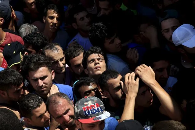 A Syrian refugee (C) tries to catch his breath as he stands in a crowded line to get registered in the national stadium of the Greek island of Kos, August 12, 2015. (Photo by Alkis Konstantinidis/Reuters)