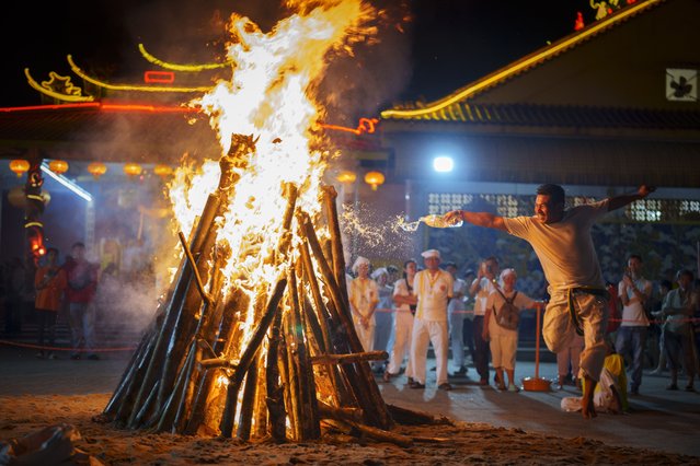 A man set wood on fire to prepare for worshippers to walk barefoot over burning coals during the Nine Emperor Gods festival at a temple in Kuala Lumpur, Malaysia, Monday, October 7, 2024. (Photo by Vincent Thian/AP Photo)