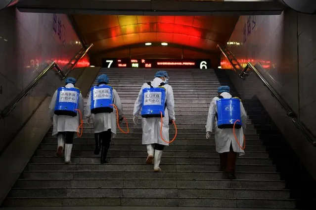 Workers with sanitizing equipment walk up a flight of stairs as they disinfect a railway station in Kunming, Yunnan province, China, February 4, 2020. (Photo by Cnsphoto via Reuters)