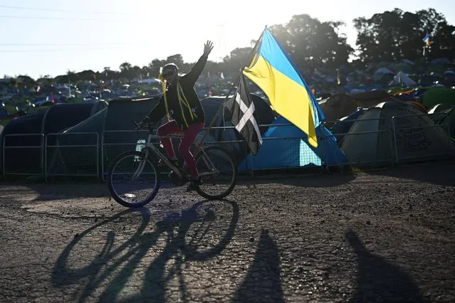 A reveller cycles with a Ukrainian flag at Worthy Farm in Somerset during the Glastonbury Festival in Britain, June 23, 2022. (Photo by Dylan Martinez/Reuters)