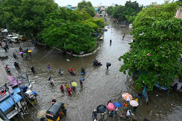 People wade through a flooded street amid heavy rainfall in Chennai on October 15, 2024. (Photo by R.Satish Babu/AFP Photo)