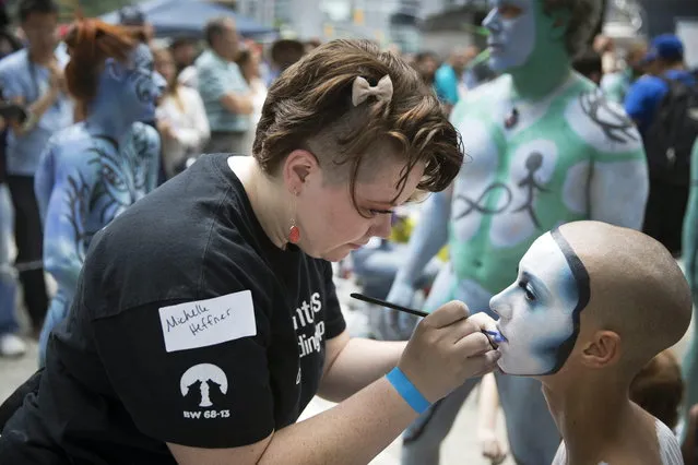 Artist Michelle Heffner, left, paints a model at Columbus Circle as body-painting artists gathered to decorate nude models as part of an event featuring artist Andy Golub, Saturday, July 26, 2014, in New York. Golub says New York was the only city in the country that would allow his inaugural Bodypainting Day. (Photo by John Minchillo/AP Photo)