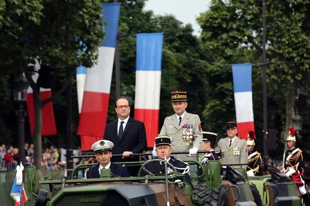 French President Francois Hollande (L) and the Chief of the Defence Staff French army General Pierre de Villiers arrive in a command car for the annual Bastille Day military parade on the Champs-Elysees avenue in Paris on July 14, 2016. (Photo by Thibault Camus/AFP Photo)