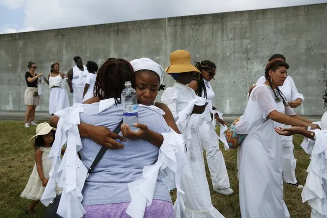 Savannah Shange (facing camera) is comforted at the site where the Industrial Canal levee failed in 2005, flooding the Lower Ninth Ward, while she participates in a ceremony marking the tenth anniversary of Hurricane Katrina in New Orleans, Louisiana, August 29, 2015. (Photo by Edmund D. Fountain/Reuters)