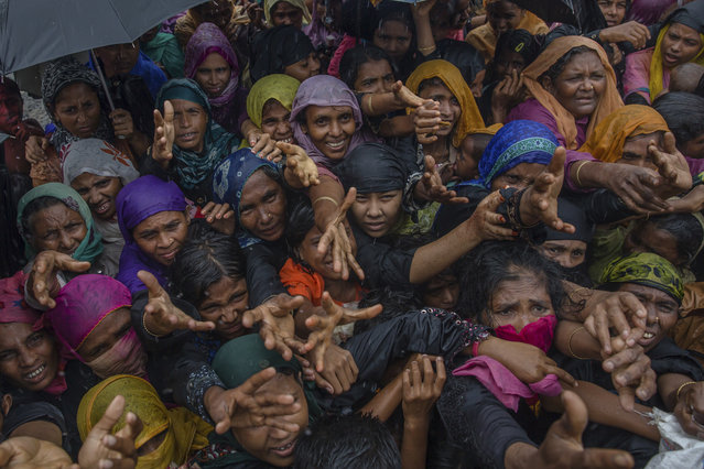 Rohingya Muslim women, who crossed over from Myanmar into Bangladesh, stretch their arms out to collect sanitary products distributed by aid agencies near Balukhali refugee camp, Bangladesh, Sunday, September 17, 2017. Bangladeshi authorities on Sunday took steps to restrict the movement of Muslim Rohingya refugees living in crowded border camps after fleeing violence in Myanmar, while that nation's military chief maintained the chaos was the work of extremists seeking a stronghold in the country. (Photo by Dar Yasin/AP Photo)