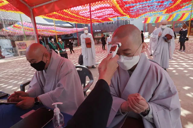 A Buddhist monk wearing a face mask is checked his temperature by a Korea Red Cross official to donate blood due to the shortage of blood donators amid the rapid spread of the new coronavirus at the Jogyesa temple in Seoul, Tuesday, March 24, 2020. (Photo by Ahn Young-joon/AP Photo)