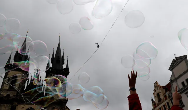 Soap bubbles float as a man balances on a line stretched over the Old Town Square in Prague, Czech Republic September 25, 2017. (Photo by David W. Cerny/Reuters)