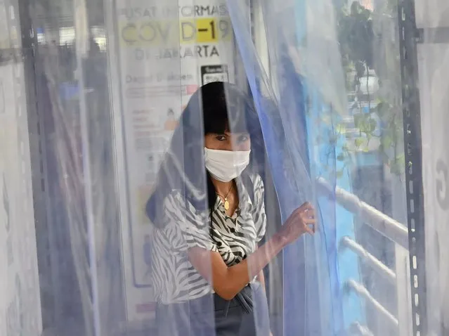 An Indonesian woman walks through a disinfection chamber as a preventive measure amid the COVID-19 coronavirus pandemic at the Harmony bus station in Jakarta on April 6, 2020. (Photo by Adek Berry/AFP Photo)