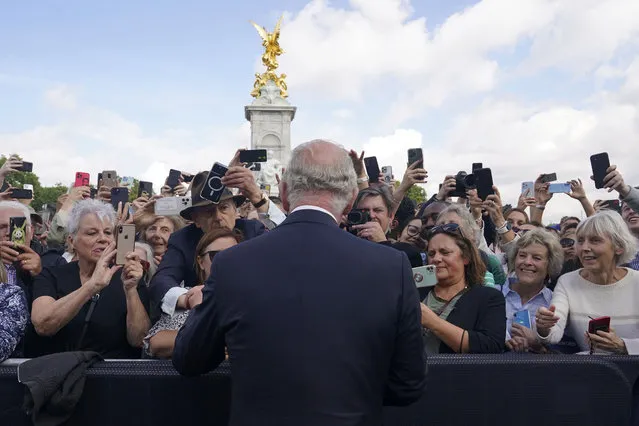 Britain's King Charles III, back to camera, greets well-wishers as he walks by the gates of Buckingham Palace following Thursday's death of Queen Elizabeth II, in London, Friday, September 9, 2022. King Charles III, who spent much of his 73 years preparing for the role, planned to meet with the prime minister and address a nation grieving the only British monarch most of the world had known. He takes the throne in an era of uncertainty for both his country and the monarchy itself. (Photo by Yui Mok/Pool Photo via AP Photo)