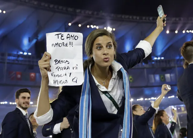 An athlete holds up a sign as she arrives with the Argentina team during the Opening Ceremony for the 2016 Summer Olympics in Rio de Janeiro, Brazil, Friday, August 5, 2016. (Photo by David J. Phillip/AP Photo)