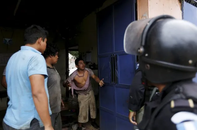 A man talks to a riot police officer who is trying to detain him during a protest against the re-election of the city's mayor Rubelio Recinos of the Patriot Party in Barberena, northwest of Guatemala City, September 8, 2015. (Photo by Jorge Dan Lopez/Reuters)