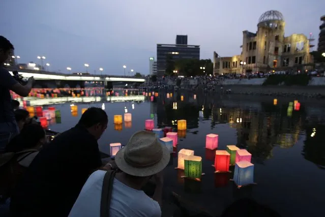 People watch floating paper lanterns released to comfort souls of victims of the 1945 atomic bombing, on the Motoyasu River with the Atomic Bomb Dome in the background at Hiroshima Peace Memorial Park in Hiroshima, western Japan, 06 August 2016. Hiroshima marked the 71st anniversary of the world's first nuclear bombing of the city on 06 August. (Photo by Kiyoshi Ota/EPA)