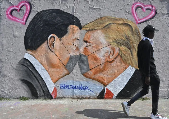 A mural painting by graffiti artist Eme Freethinker features likenesses of US President Donald Trump (R) and Chinese premier Xi Jinping wearing face covers in Berlin on April 28, 2020 amid the new coronavirus COVID-19 pandemic. (Photo by John Macdougall/AFP Photo)