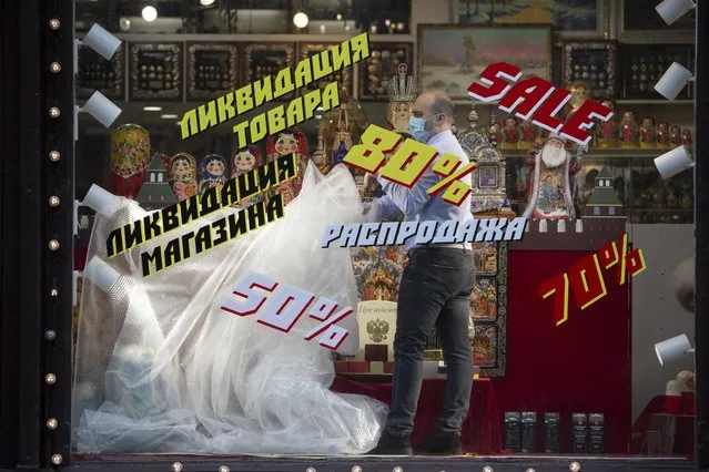 An employee removes a plastic cover from goods at the shop window after reopening in Moscow, Russia, on Monday, June 1, 2020. Monday's reopening of retail stores along with dry cleaners and repair shops comes as the pace of contagion has stabilized in the Russian capital that has accounted for about half of the nation's infections. (Photo by Alexander Zemlianichenko Jr./AP Photo)