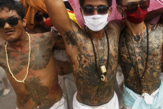 Devotees of the Chinese Bang Neow Shrine covered in tattoos react amidst exploding firecrackers during a procession celebrating the annual vegetarian festival in Phuket September 29, 2014. (Photo by Damir Sagolj/Reuters)