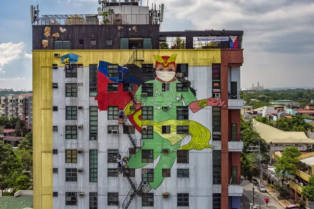 Filipino artists from the group “Art Attack” paint a mural depicting Darna, a fictional Filipino comics superhero, wearing a scrub suit and protective mask on the side of a building to honour health workers fighting against COVID-19, on May 18, 2020 in Quezon city, Metro Manila, Philippines. The Philippine government began easing quarantine measures in many areas of the country, but has extended the lockdowns in Manila and a few other cities until May 31. Manila's lockdown, one of the worlds strictest, will extend to 80 days longer than the 76-day lockdown of Wuhan, the Chinese city that was the early epicenter of COVID-19. The Philippines' Department of Health has so far reported 12,513 cases of the coronavirus in the country, with at least 824 recorded fatalities. (Photo by Ezra Acayan/Getty Images)
