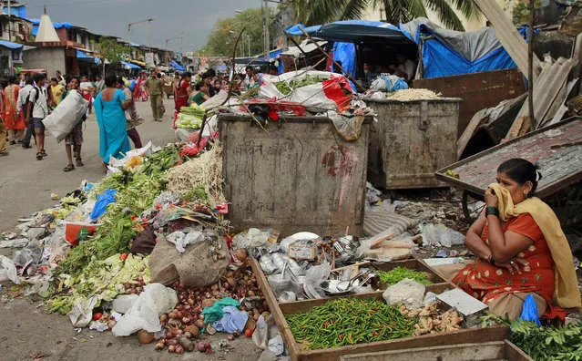 An Indian vegetable vendor covers her nose from the smell of garbage scattered on the road in Mumbai, India, Wednesday, October 1, 2014. October 2, Mahatma Gandhi's birth anniversary, is usually a public holiday across India. This year, however, the government has ordered officials in India's gargantuan bureaucracy and schoolchildren from all the city schools to take the pledge to spread the message of cleanliness and tidy up their offices, schools and nearby streets. (Photo by Rafiq Maqbool/AP Photo)