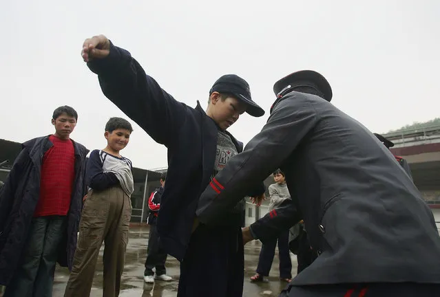 A security guard frisks boys after one kid's money was stolen at an assistance center February 24, 2005 in Shenzhen, Guangdong Province, China. (Photo by Cancan Chu/Getty Images)