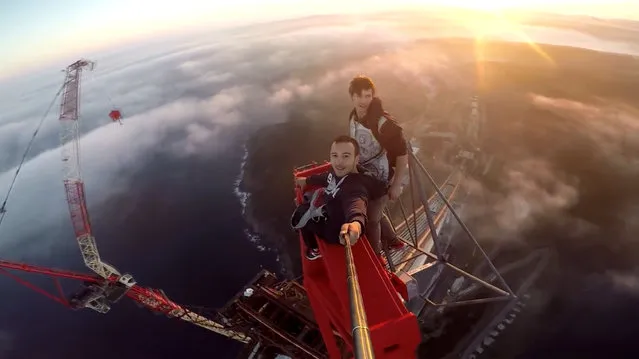 Pavel Smirnov and his friend ontop of the top of the Yavuz Sultan Selim Bridge in Istanbul, Turkey on May 17, 2016. Fearless Pavel climbed up to the top of the Yavuz Sultan Selim Bridge  the tallest building in Turkey, and the second tallest bridge in the world. Daring Pavel and his pal dangled precariously over the edge of the 350m high bridge, looking like they were on the edge of the world as they sat high above the clouds. The duo happily risked their lives as they scaled dizzying heights to reach the top of the bridge  all so they could snap the ultimate selfie. (Photo by Pavel Smirnov/Caters News Agency)