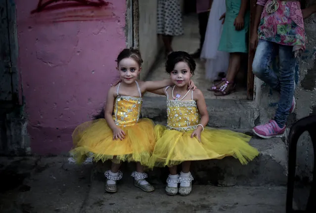 In this Saturday, July 30, 2016 photo, two girls pose for a picture as they sit in front of the family house during the wedding party of Palestinian groom Saed Abu Aser, in Gaza City. Weddings have emerged as a welcome celebration that slices through the often morose mood in the Gaza Strip, a Palestinian coastal territory run by the militant group Hamas. For both poor and well-off Gazans, weddings are a days-long, lavish affair of parties and dancing. (Photo by Khalil Hamra/AP Photo)