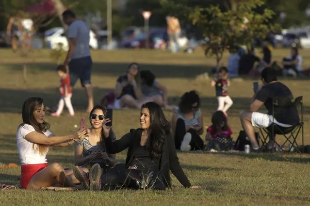 People gather in the late afternoon to watch the sunset at a park in the city center, after authorities eased restrictions related to COVID-19, in Brasilia, Brazil, Saturday, July 4, 2020. (Photo by Eraldo Peres/AP Photo)