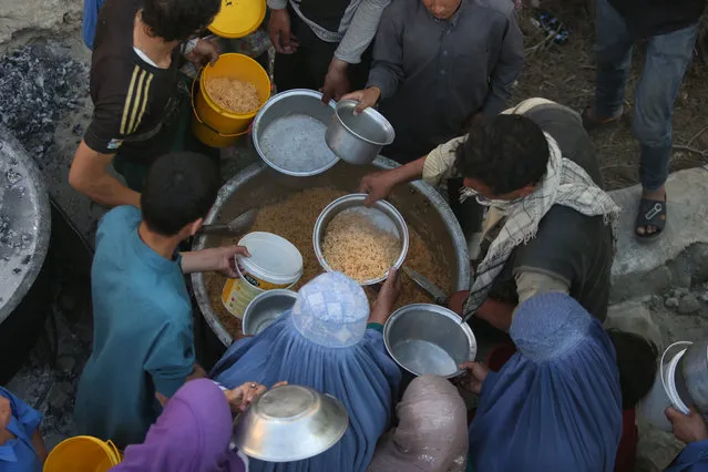 In this Thursday, June 9, 2016 photo, Afghan women and children receive free food donated by other villagers as they prepare to break their fast during the holy month of Ramadan in Kabul, Afghanistan. Fifteen years ago as the United States prepared to invade Taliban-ruled Afghanistan, then-First Lady Laura Bush took over her husband’s weekly radio address to tell the American people that part of the reason for going to war after the attacks of September 11, 2001, was to liberate Afghan women from the brutality of the extremists’ regime. But abuse of women in Afghanistan remains entrenched and endemic, despite constitutional guarantees of equality.(Photo by Rahmat Gul/AP Photo)
