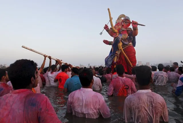 Devotees try to immerse an idol of Hindu elephant god Ganesh, the deity of prosperity, into the Arabian Sea on the last day of the Ganesh Chaturthi festival in Mumbai, India, September 27, 2015. (Photo by Danish Siddiqui/Reuters)