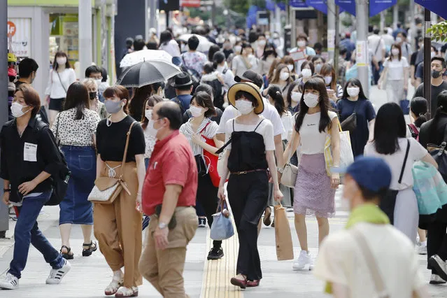 People make their way on a street in Tokyo Sunday, August 2, 2020. Confirmed coronavirus cases are hovering at near record levels in Japan, raising worries the pandemic may be growing more difficult to control. The Tokyo government reported more than 290 new cases Sunday, about half in their 20s. (Photo by Kyodo News via AP Photo)