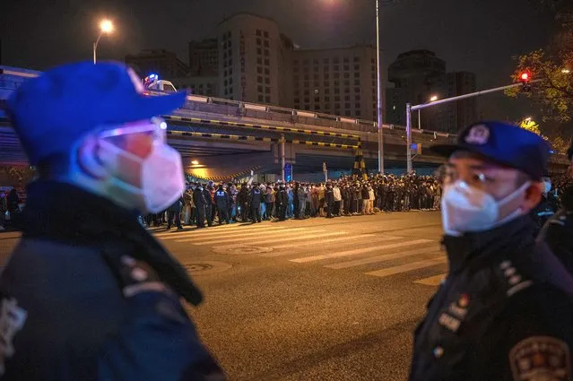 Police stand as part of a cordon during a protest against Chinas strict zero COVID measures on November 28, 2022 in Beijing, China. Protesters took to the streets in multiple Chinese cities after a deadly apartment fire in Xinjiang province sparked a national outcry as many blamed COVID restrictions for the deaths. (Photo by Kevin Frayer/Getty Images)