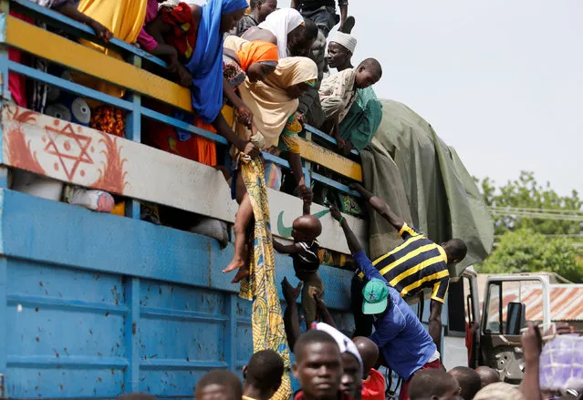 Parents lower their children from a loaded truck at a local bus station in Maiduguri, Borno State, Nigeria, August 30, 2016. (Photo by Afolabi Sotunde/Reuters)
