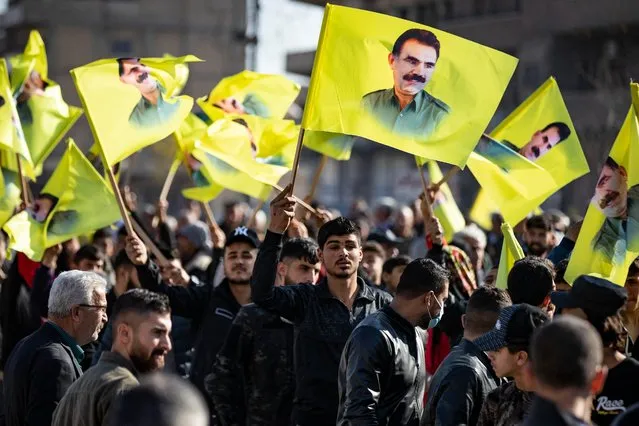 Protesters march with yellow flags showing the face of Abdullah Ocalan, the leader of the Kurdistan Worker's Party (PKK) – currently prison in Turkey, during a demonstration calling for his release and condemning recent Turkish strikes on Kurdish areas, in the Kurdish-majority city of Qamishli in northeastern Syria on December 6, 2022. (Photo by Delil Souleiman/AFP Photo)